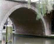 843696 Gezicht door een van de bogen van de Jacobibrug over de Oudegracht te Utrecht, voor de restauratie van de brug.